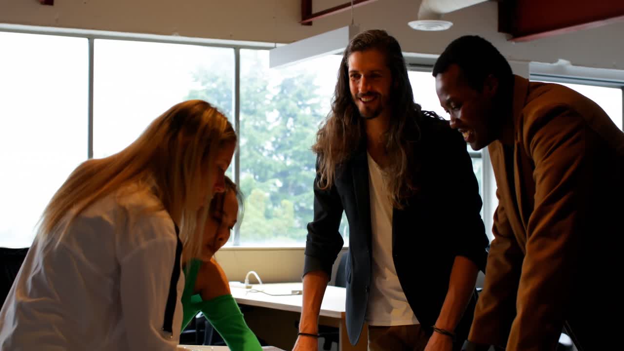 Business colleagues discussing over blueprint in office 4k