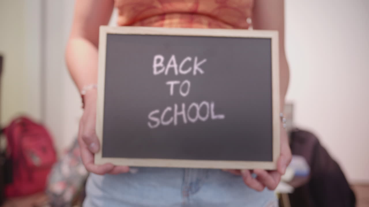 Person Holding 'Back to School' Blackboard