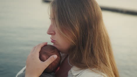 tender moment of mother holding newborn by the water