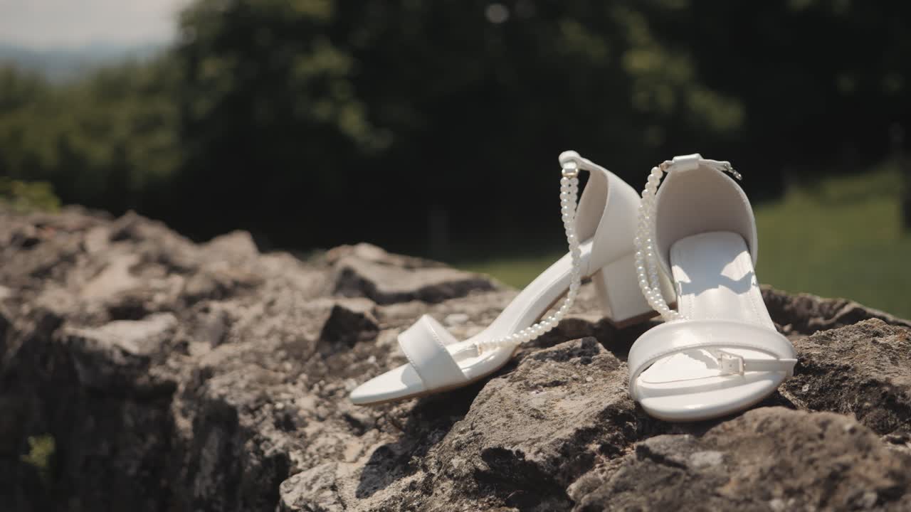 White wedding heels on stone wall in sunny outdoor setting, serene vibe