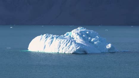 iceberg in fjord by coastline on greenland on sunny summer day