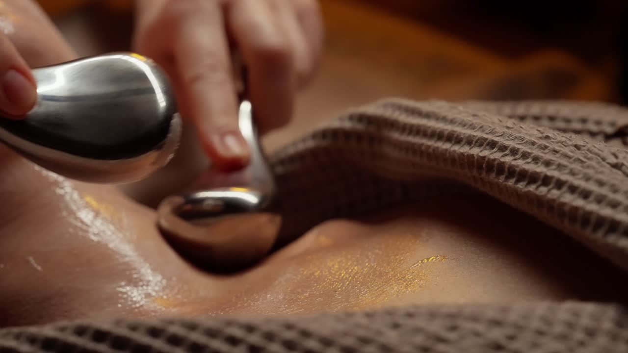Nærbillede af professionel nakke- og ansigtsmassage med metalredskaber