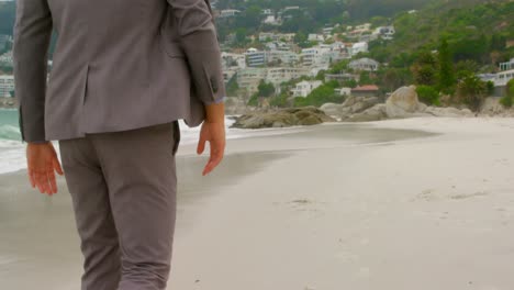 Rear-view-of-Caucasian-man-walking-barefoot-on-the-beach-4k