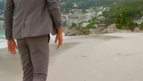 vista trasera de un hombre caucásico caminando descalzo en la playa 4k