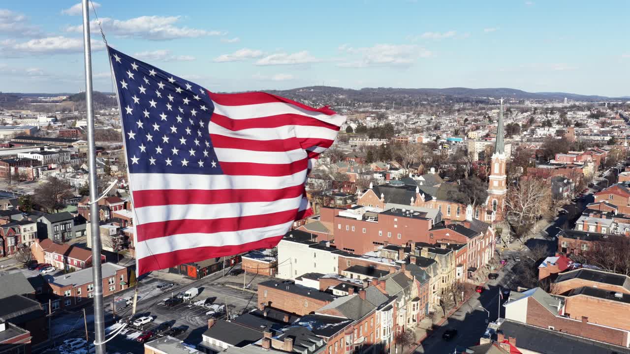 Bandiera americana sventolante su una piccola città storica negli Stati Uniti durante una giornata di sole invernale. Edifici e case in mattoni rossi a York, Pennsylvania. Ripresa aerea statica ravvicinata. Città patriottica negli Stati Uniti.