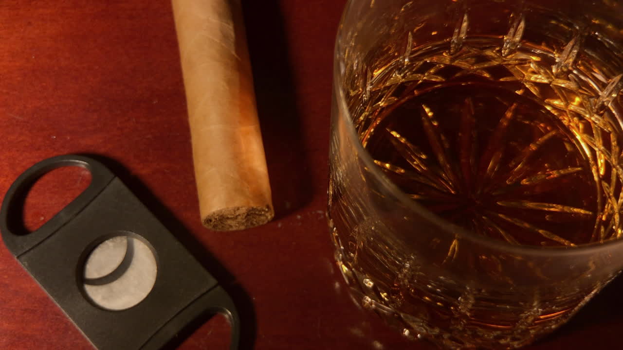 el vaso de whisky, el cigarro y el cortador de cigarros se sientan en la parte superior de la barra de caoba