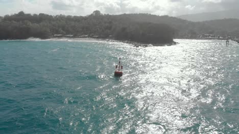 aerial shot of a red buoy at the entrance to the port of padang bai, bali, indonesia