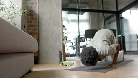 african american man doing yoga and stretching at home, slow motion