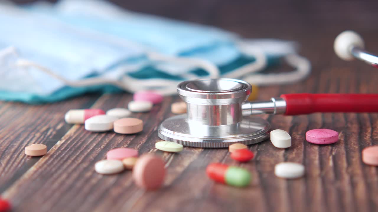 estetoscópio, comprimidos e máscaras numa mesa de madeira
