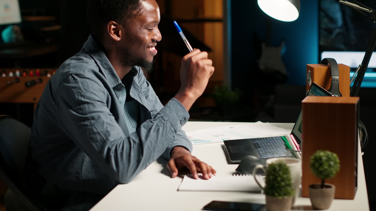 Self employed Black man multitasking at home taking handwritten notes