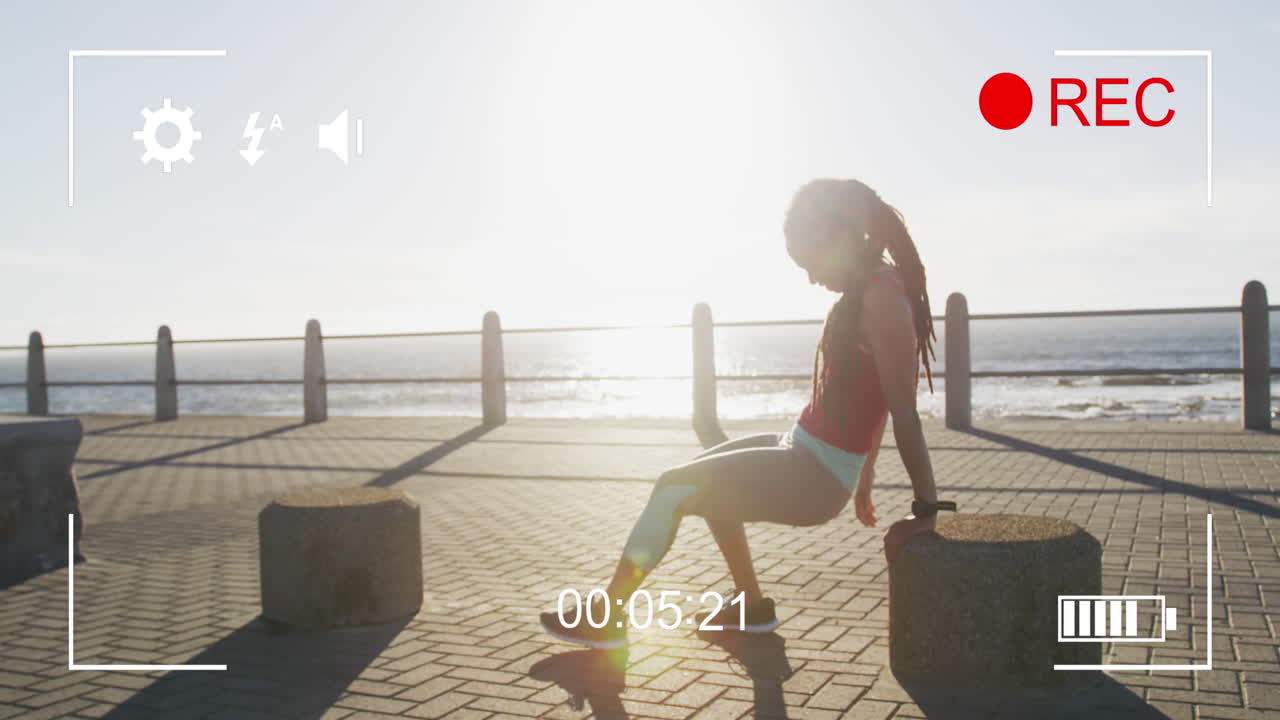 Digital camera interface against tired african american fit woman sitting on the promenade