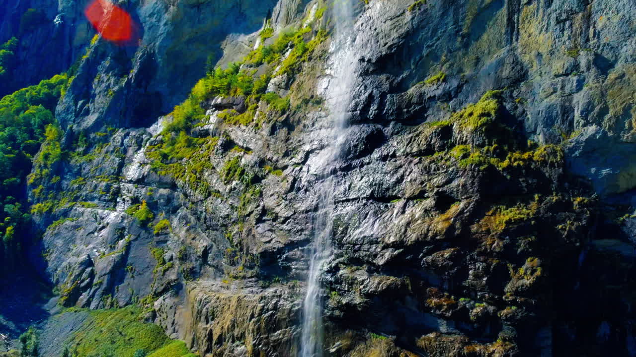 disparo calmante de un dron flotante de una cascada icónica que fluye al mediodía en lauterbrunnen, suiza, europa, vista amplia