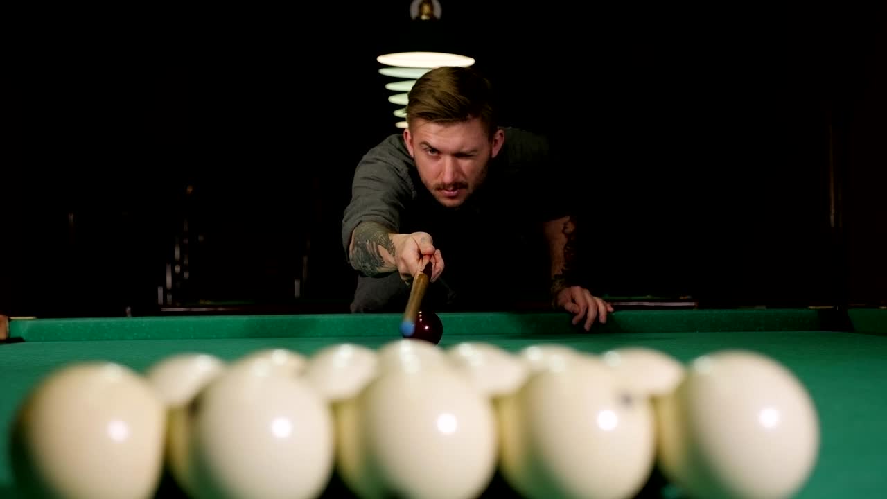 un joven guapo y exitoso jugando al billar ruso en un bar con amigos.