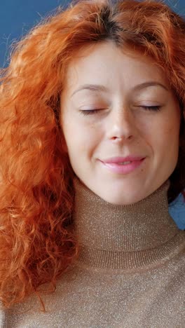 smiling woman with curly red hair wearing a cozy turtleneck sweater, showcasing warmth and approachability in a bright indoor setting with soft lighting