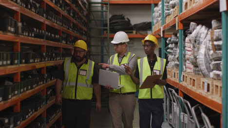 two caucasian and an african american male factory worker at a factory wearing hard hats and glasses