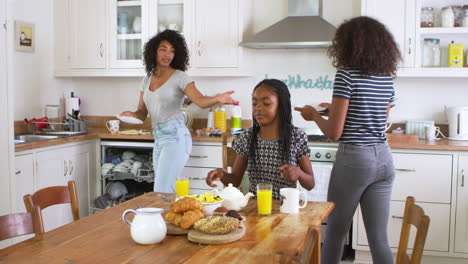 las hijas ayudando a la madre a limpiar la mesa después del desayuno familiar