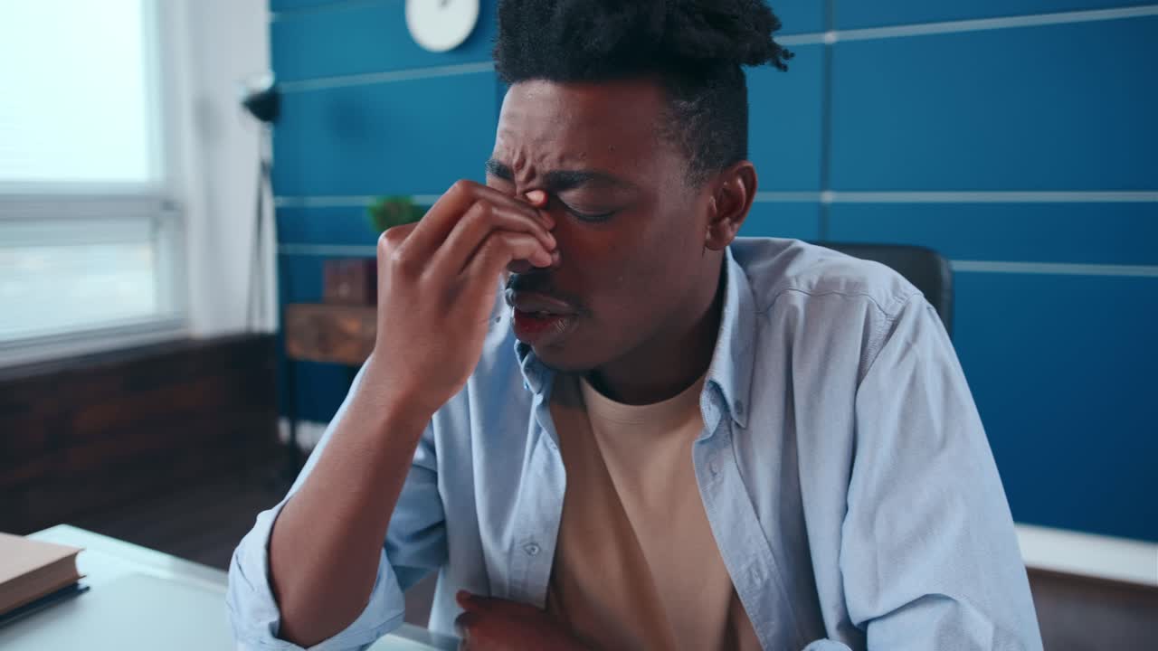 Tired young business man wearing shirt rubbing bridge of nose fighting headache