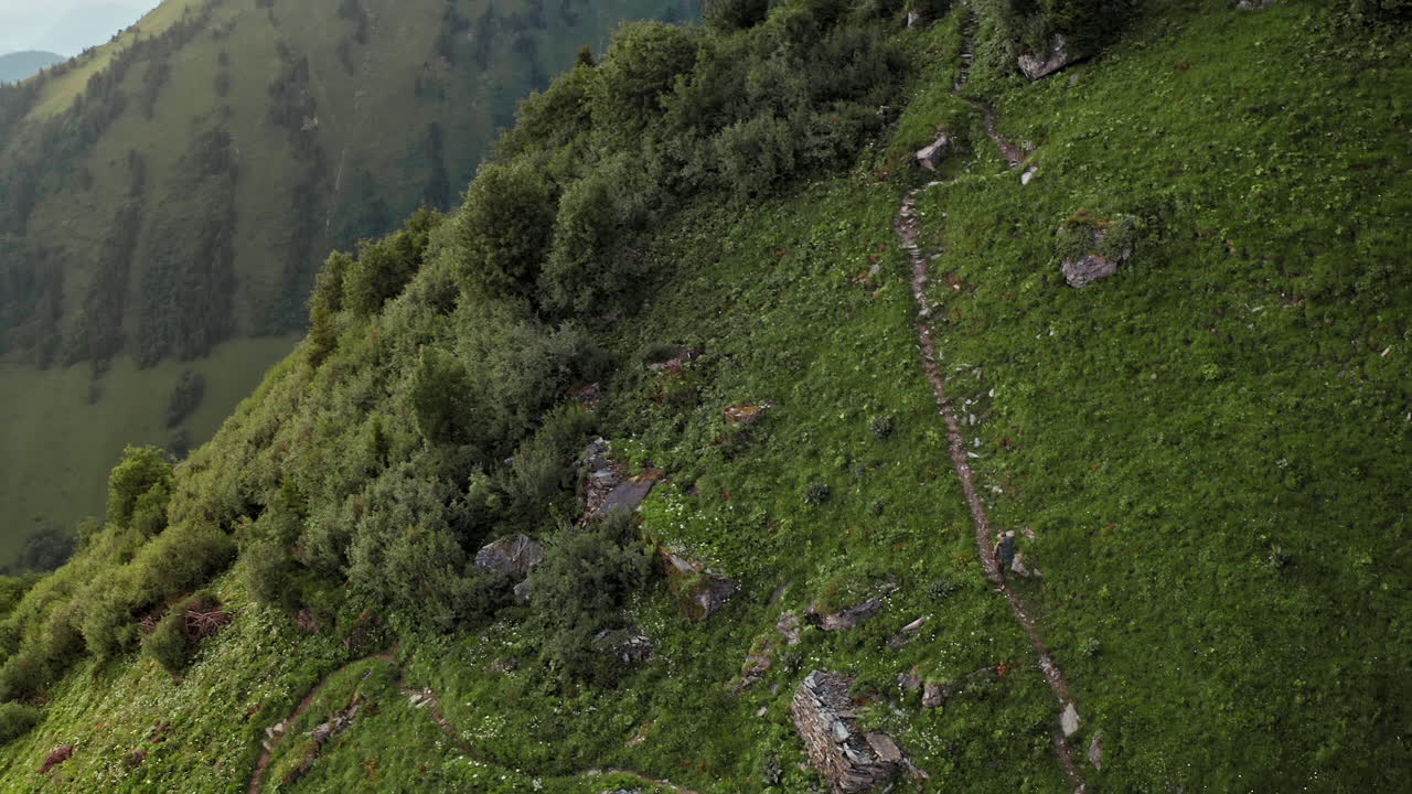 vista aérea cinematográfica de un caminante solitario caminando por un sendero de montaña al amanecer