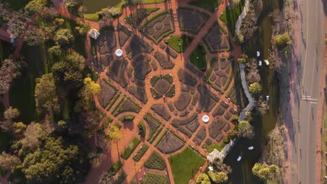 Top-down-view-of-the-Rosedal-De-Palermo-without-people-in-Buenos-Aires,-Argentina-and-a-road-on-the-left-side-with-people-walking-on-it