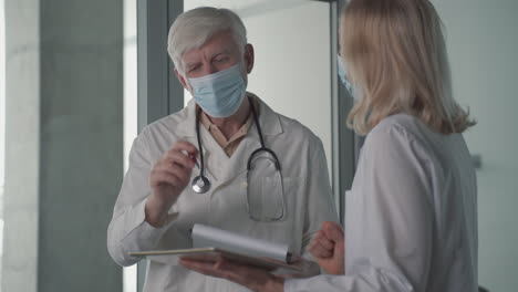 a pair of doctors with masks converse while looking at results 1