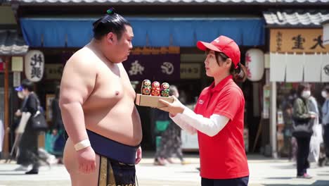 A humorous encounter between a sumo wrestler and a vendor, showcasing the cultural blend of traditional sports and modern street food in a lively marketplace setting