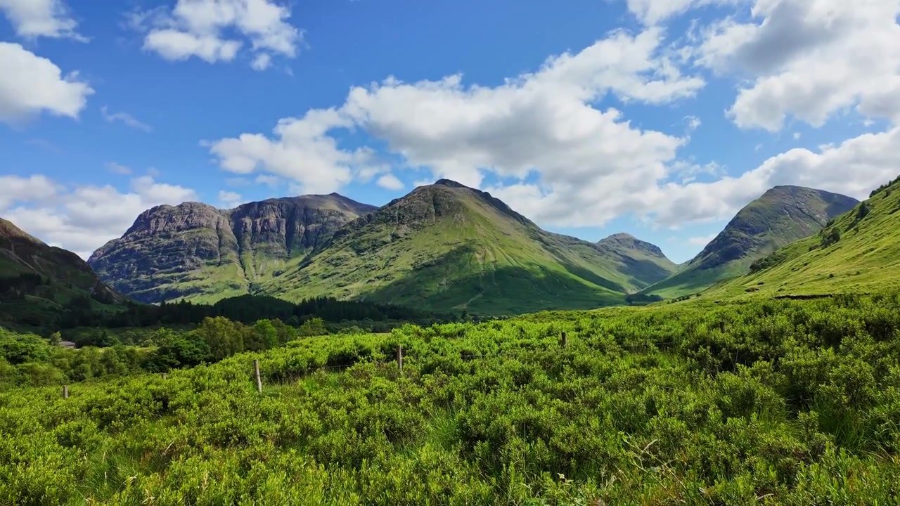 Splendida panoramica di una magnifica valle verde circondata da imponenti catene montuose nelle Highlands di Glencoe, Scozia.