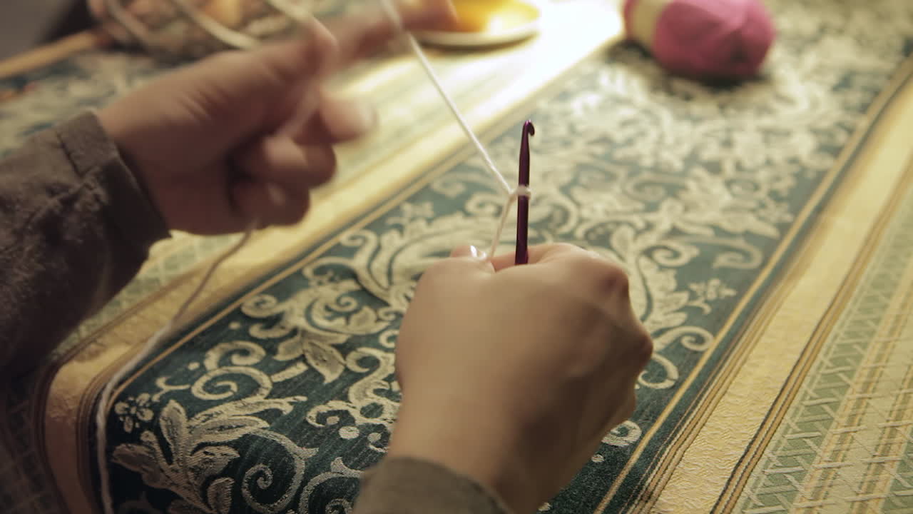 Hands intricately thread yarn through crochet hooks and needles, close-up