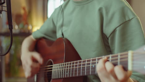 mujer asiática tocando la guitarra y grabando canciones en casa