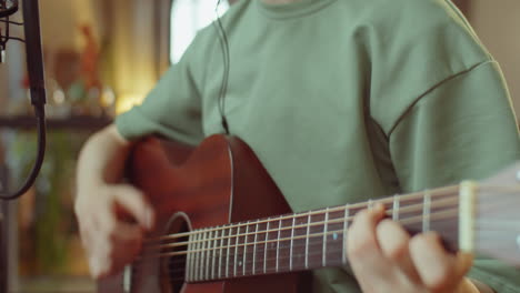 asian woman playing guitar and recording song at home