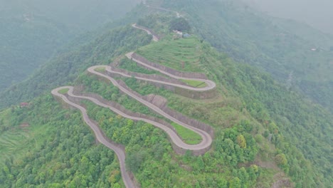 a serpentine road curves gracefully through vibrant green mountains, offering a breathtaking view of natural beauty and human engineering in harmony, captured from a high-altitude aerial perspective.