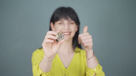 mujer sosteniendo bitcoin y mostrándolo.