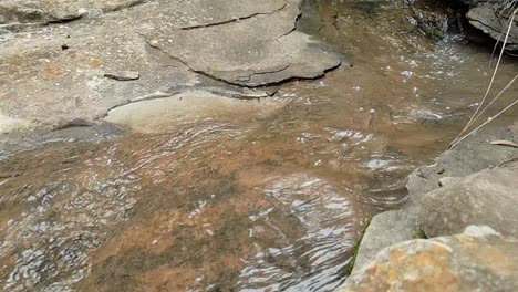 Fließendes-Wasser-Aus-Einem-Bergquellwasserstrom,-Der-Riesige-Sandsteinfelsen-Mit-Grünen-Pflanzen-Hinunterfließt,-Kristallklares-Trinkwasser,-Meditiert-Ruhige-Und-Friedliche-Zeitlupenaufnahmen