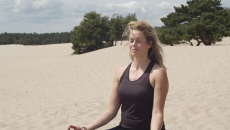 beautiful woman meditating in peaceful sand dunes