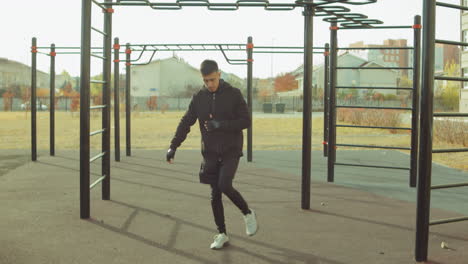 athletic man doing single leg hip rotation on workout playground