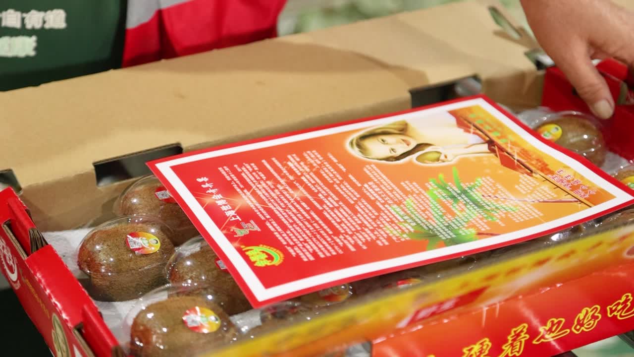 Finalization of kiwi packing on a production line, with workers efficiently packing the fruit into boxes at a factory in Shaanxi Province, China.