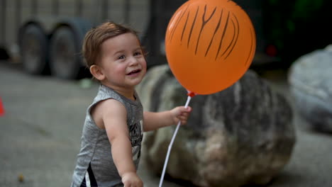 niño mexicano americano de dos razas con un globo naranja