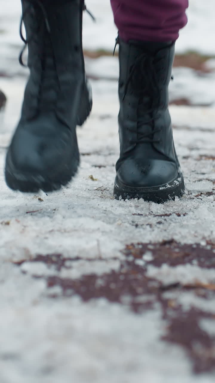 vista de la pierna de una persona con botas negras corriendo en un parque al aire libre en un entorno urbano, clima frío, nieve en el suelo, acondicionamiento físico en invierno, ejercicio al aire libre durante el día frío, parque infantil visible