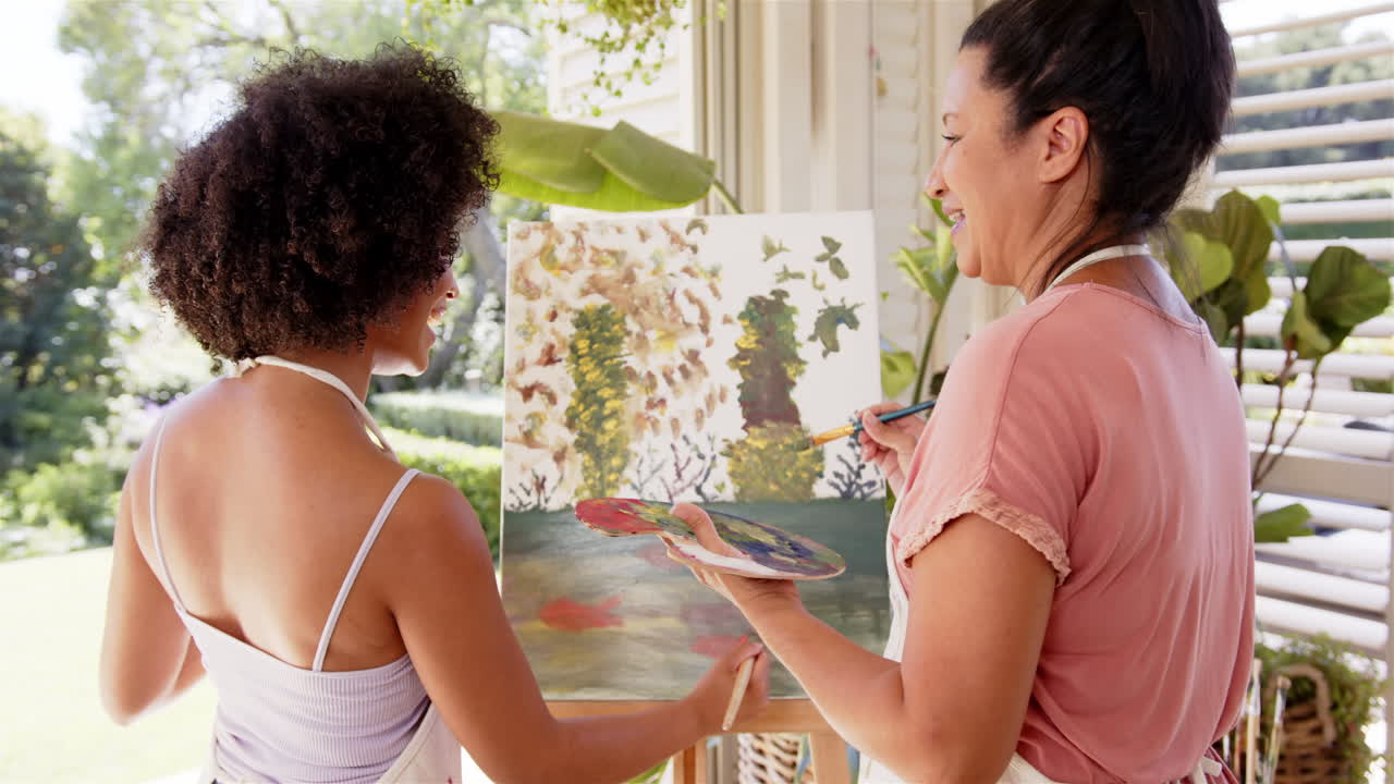 Painting on canvas, mother and adult daughter enjoying art activity together indoors