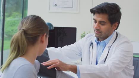 male doctor or gp examining teenage girl taking blood pressure with sphygmomanometer