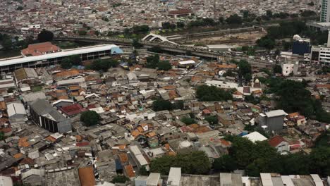 aerial view over poor slum district in jakarta city with skyline in backdrop - border between luxury and poverty