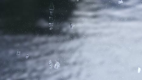 raindrop on windows, with a flowing river blur the background