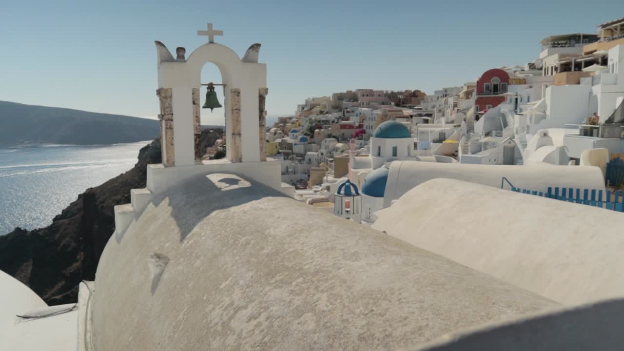 pan vertical y revelación de campanas de iglesia griegas blancas con vistas al mar en santorini, grecia