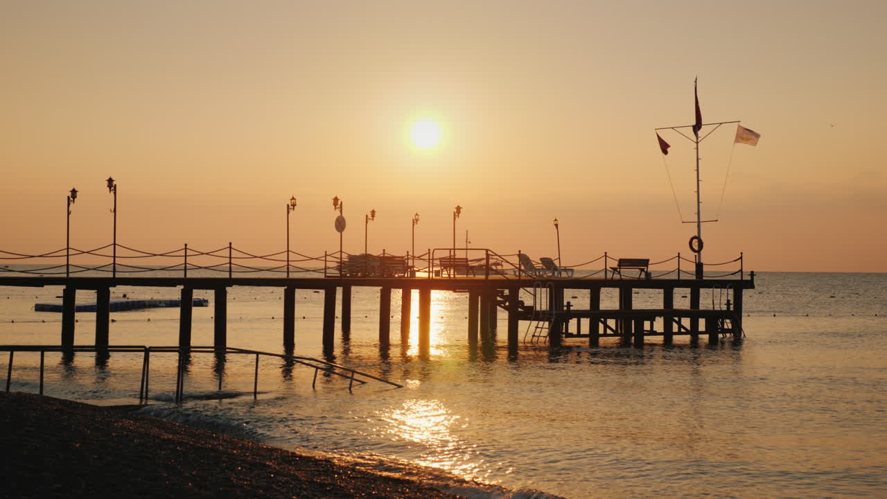 물속으로 튀어나온 부두의 바다 실루엣 위로 새벽 - 여름의 경치 좋은 풍경