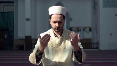 man kneeling and praying in a mosque wearing religious clothing