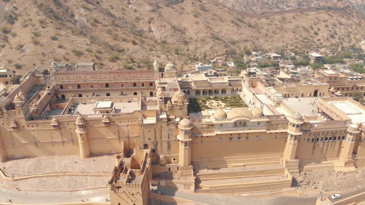 amplia vista al fuerte ámbar jaleb chowk y aram bagh rodeados de colinas áridas en jaipur, rajasthan, india - toma de órbita panorámica aérea amplia