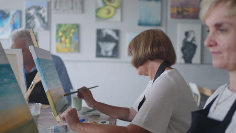 like senior friends attending together at a painting class. small group taking a variety of fun classes together. a group of elderly people attend a master class on drawing together spending time.