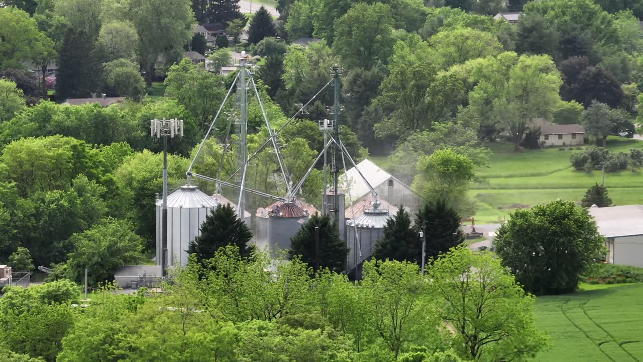 Aerial view of farm architecture with prominent metal silos and traditional barns set amidst verdant trees.Modern agricultural structures with classic rural design. American countryside in May. PA,USA