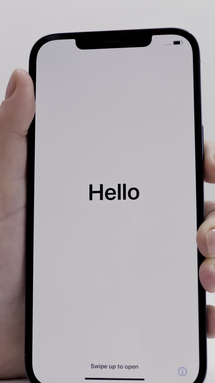 Persona che tiene in mano un iPhone con la schermata 'Hello'