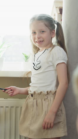 smiling girl asks little brother to solve maths tasks standing by chalkboard at home. elder sister teaches toddler boy mathematics lesson in children room