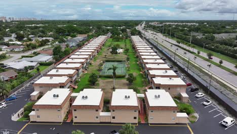 aerial flyover apartment houses with private tennis field in suburb of naples city beside highway. florida, usa.